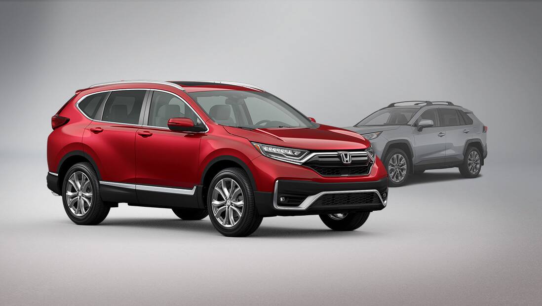 Front passenger-side view of the 2020 Honda CR-V Touring, in Deep Scarlet Pearl, parked in studio environment next to a Toyota RAV4.