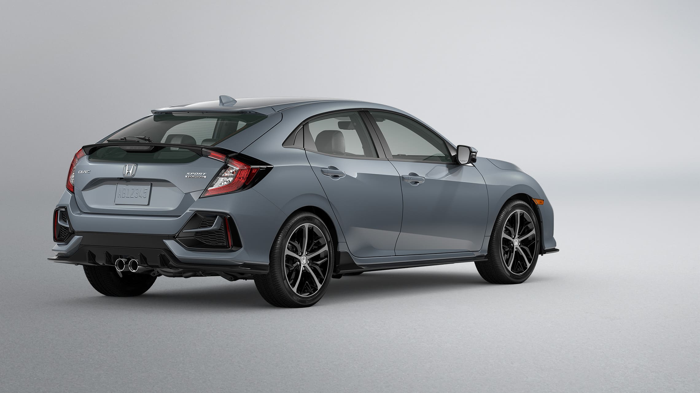 Vista trasera de 3/4 del lado del conductor del Honda Civic Sport Touring Hatchback 2020 en Sonic Gray Pearl.