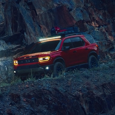 2027 Honda Passport TrailSport Elite in Radiant Red Metallic II front parked on a steep rocky (Mid-Size SUV).
